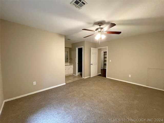 unfurnished bedroom featuring light carpet, ensuite bath, and ceiling fan