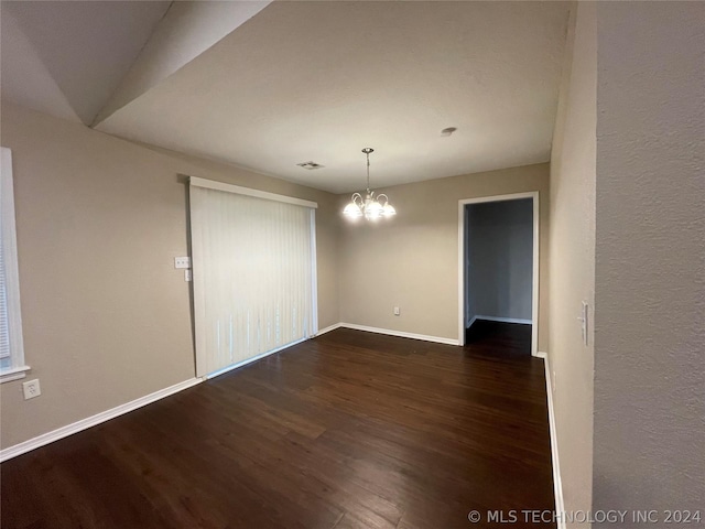 spare room featuring a chandelier, dark hardwood / wood-style flooring, and vaulted ceiling