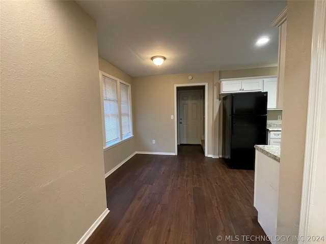 kitchen with black fridge, white cabinetry, and dark wood-type flooring