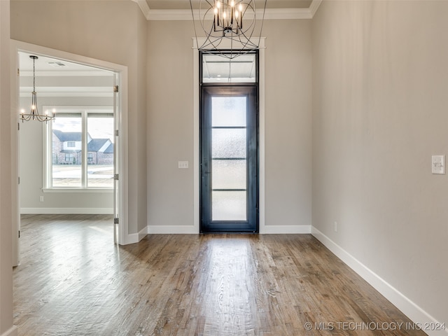 foyer entrance with hardwood / wood-style floors, crown molding, and an inviting chandelier