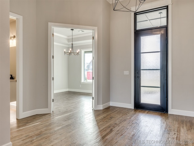 foyer with a chandelier, hardwood / wood-style floors, and crown molding