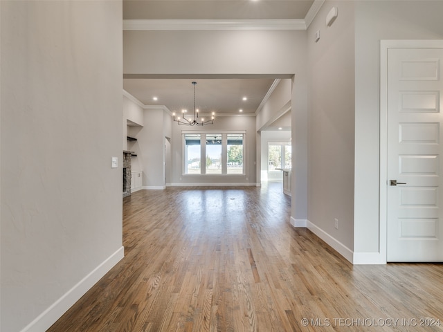 unfurnished living room with light hardwood / wood-style flooring, ornamental molding, and a notable chandelier