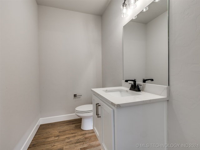 bathroom with hardwood / wood-style floors, vanity, and toilet