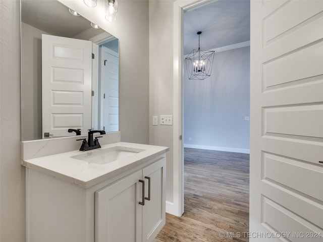 bathroom with ornamental molding, vanity, wood-type flooring, and a notable chandelier