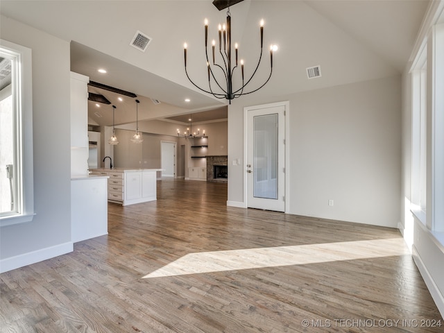 unfurnished living room with sink, light hardwood / wood-style floors, and lofted ceiling