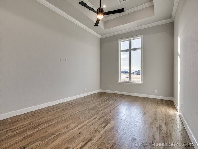 spare room with hardwood / wood-style floors, ceiling fan, a raised ceiling, and crown molding