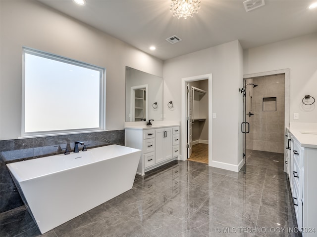 bathroom featuring plus walk in shower, vanity, and an inviting chandelier