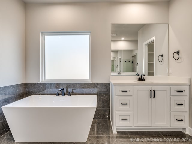 bathroom with a washtub, vanity, and tile walls