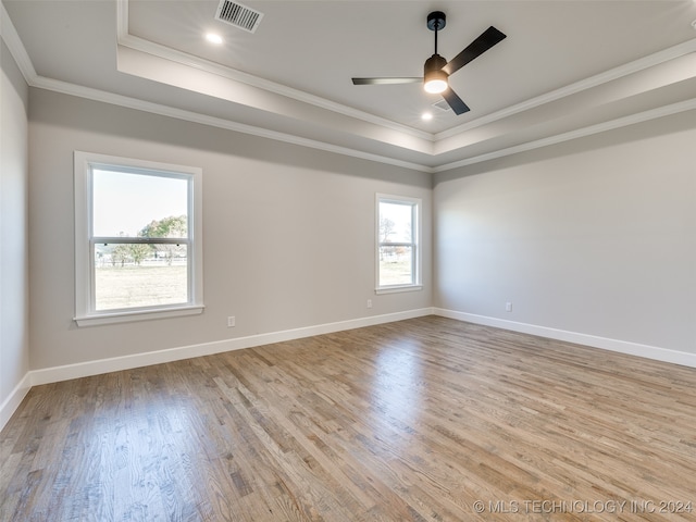 spare room featuring light wood-type flooring, a tray ceiling, ceiling fan, and crown molding