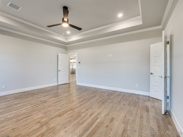 unfurnished room featuring light wood-type flooring, a tray ceiling, ceiling fan, and crown molding