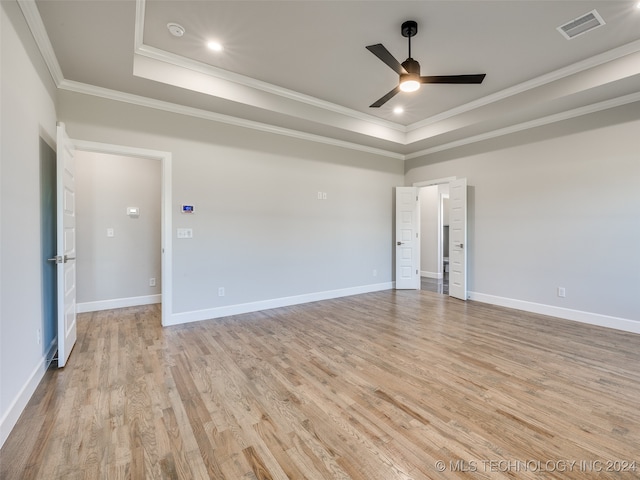 spare room featuring ceiling fan, light hardwood / wood-style floors, crown molding, and a tray ceiling