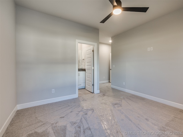 unfurnished bedroom featuring ceiling fan, ensuite bathroom, and light colored carpet