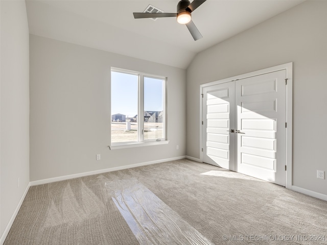 spare room featuring light carpet, vaulted ceiling, and ceiling fan