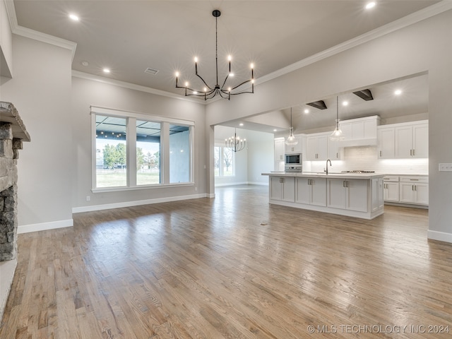 unfurnished living room featuring a stone fireplace, crown molding, light hardwood / wood-style flooring, and sink