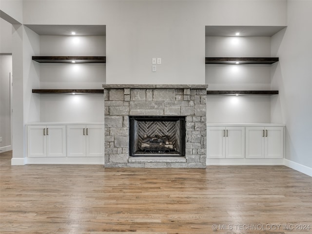 unfurnished living room with a fireplace, built in shelves, and light wood-type flooring