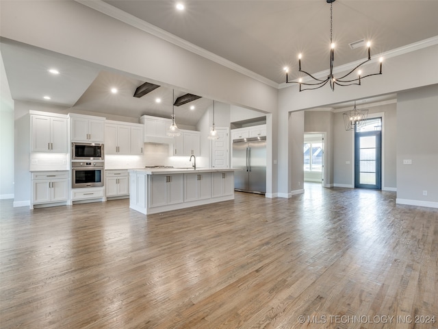 kitchen with white cabinets, light wood-type flooring, built in appliances, and hanging light fixtures