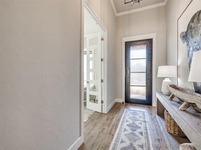 doorway with crown molding and light wood-type flooring