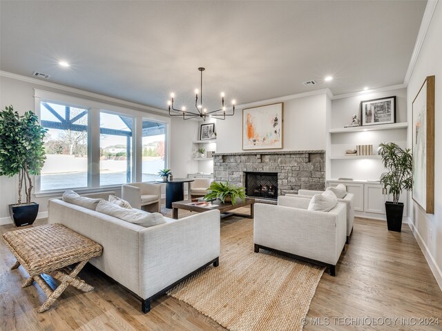 living room featuring a chandelier, ornamental molding, a fireplace, and light hardwood / wood-style flooring