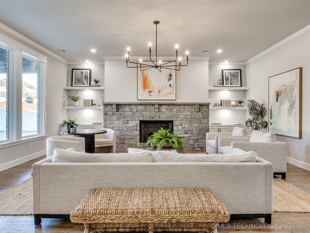 living room with a fireplace, hardwood / wood-style floors, ornamental molding, and a notable chandelier