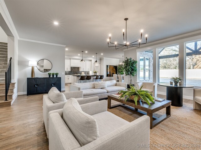 living room featuring an inviting chandelier, light wood-type flooring, and ornamental molding