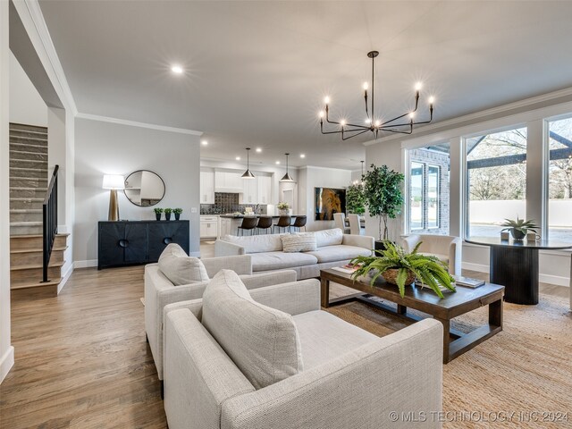 living room with crown molding, light hardwood / wood-style flooring, and an inviting chandelier