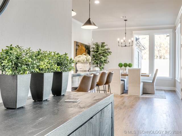 dining space with a chandelier, wood-type flooring, a wealth of natural light, and crown molding