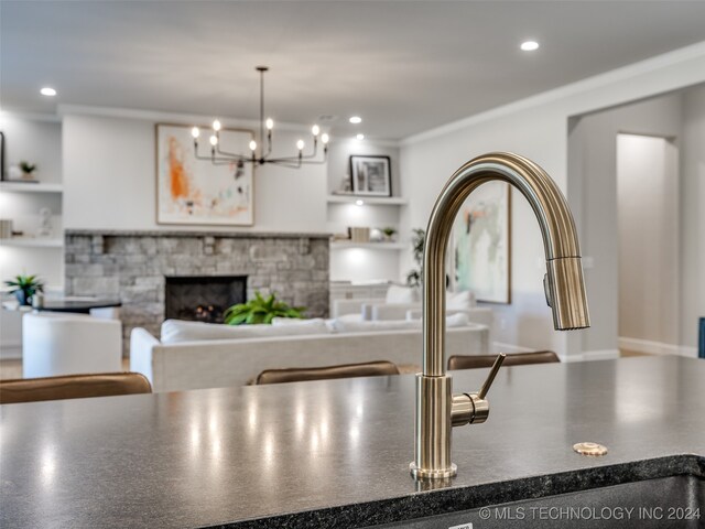 kitchen featuring a stone fireplace, crown molding, and an inviting chandelier