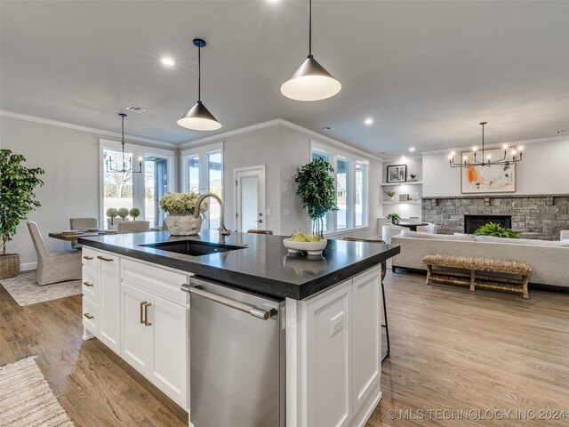 kitchen featuring a stone fireplace, stainless steel dishwasher, light hardwood / wood-style floors, a kitchen island with sink, and white cabinets