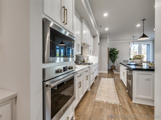 kitchen featuring crown molding, sink, white cabinets, and light hardwood / wood-style floors