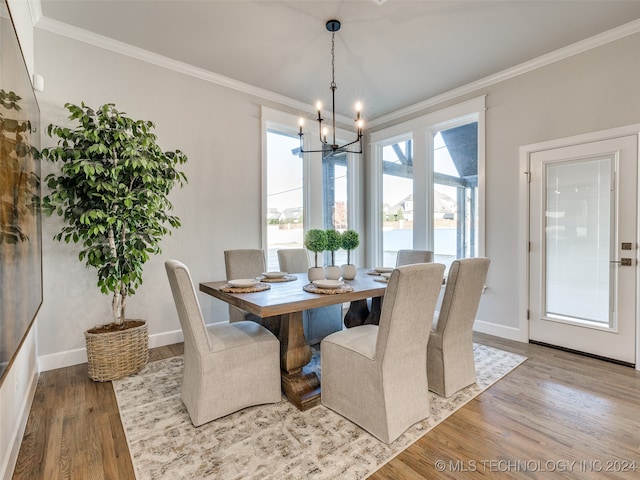 dining room featuring light wood-type flooring, crown molding, and a notable chandelier