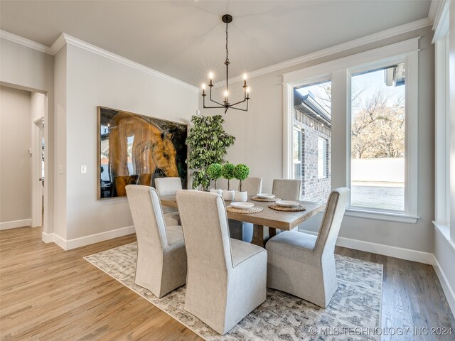 dining area with an inviting chandelier, wood-type flooring, and ornamental molding