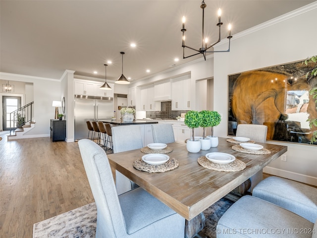 dining space featuring light hardwood / wood-style flooring, crown molding, and a notable chandelier