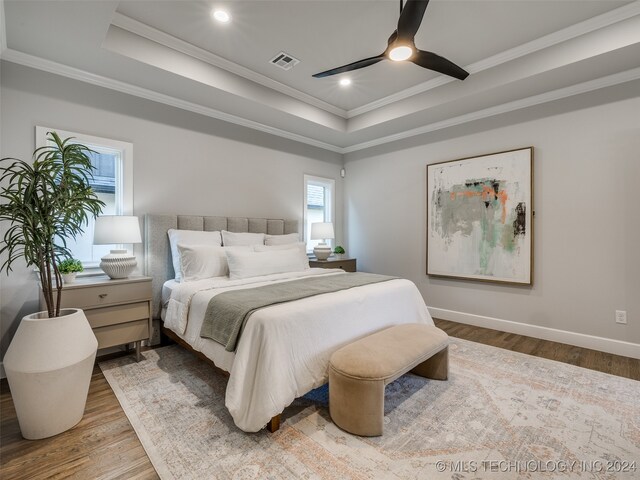 bedroom with a raised ceiling, ceiling fan, crown molding, and light hardwood / wood-style floors