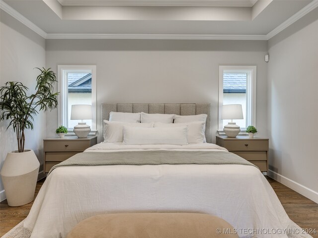 bedroom featuring dark hardwood / wood-style flooring, crown molding, a tray ceiling, and multiple windows