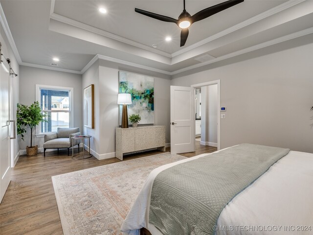 bedroom with a tray ceiling, crown molding, light hardwood / wood-style flooring, and ceiling fan