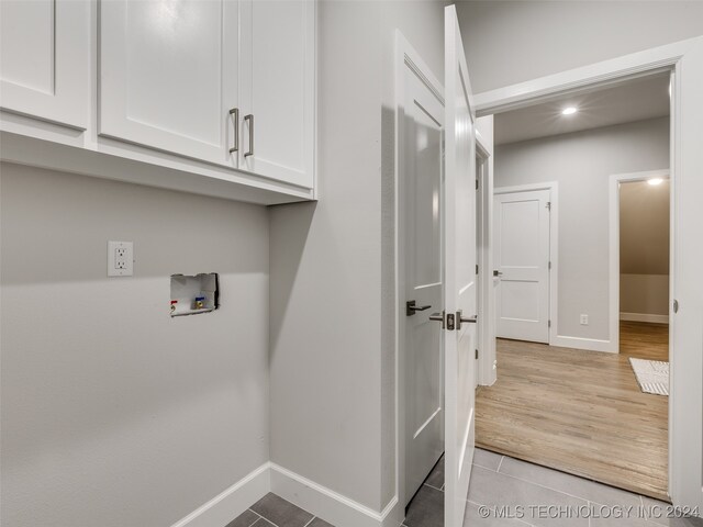 washroom featuring cabinets, hookup for a washing machine, and light hardwood / wood-style flooring