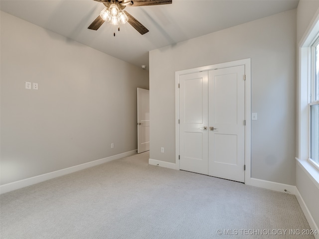 unfurnished bedroom featuring a closet, light colored carpet, and ceiling fan