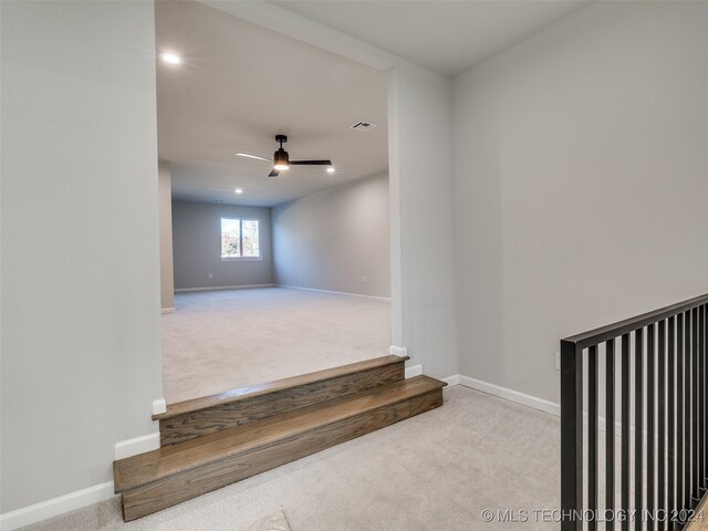 stairs featuring ceiling fan and carpet floors