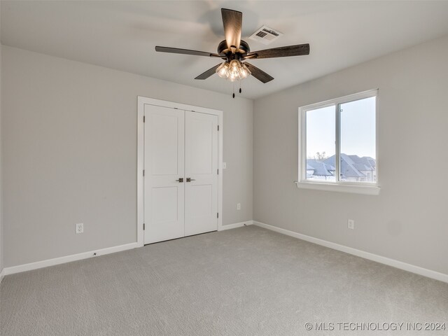 unfurnished bedroom featuring light carpet, a mountain view, a closet, and ceiling fan