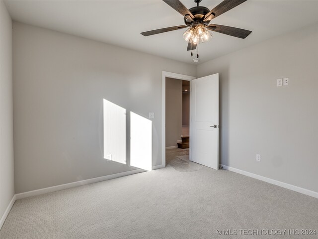 carpeted spare room featuring ceiling fan