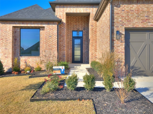 view of exterior entry with a garage and a yard