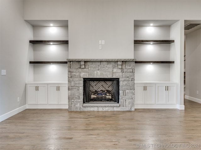 unfurnished living room featuring a fireplace, light wood-type flooring, and built in features