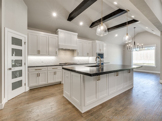 kitchen with stainless steel appliances, hardwood / wood-style flooring, white cabinets, vaulted ceiling with beams, and a large island