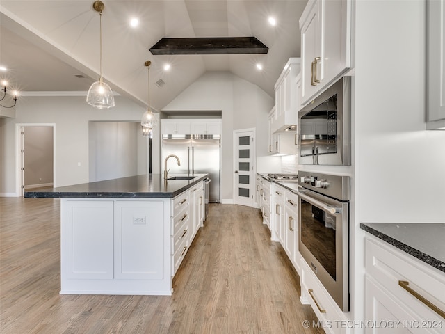 kitchen with stainless steel appliances, white cabinetry, and a kitchen island with sink