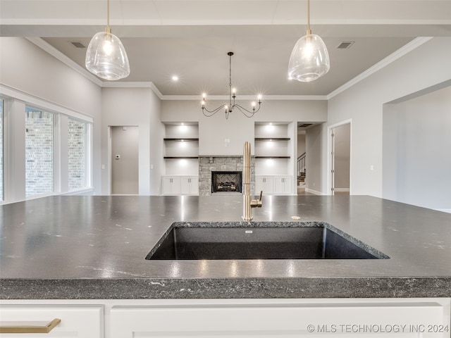 kitchen featuring a fireplace, sink, hanging light fixtures, and ornamental molding