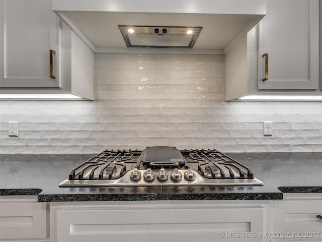 kitchen with white cabinets, backsplash, and stainless steel gas stovetop