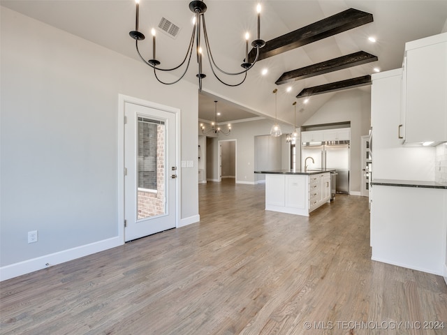 kitchen featuring white cabinetry, hanging light fixtures, beamed ceiling, a kitchen island with sink, and light wood-type flooring