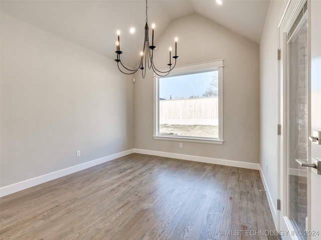 unfurnished dining area featuring a notable chandelier, vaulted ceiling, and hardwood / wood-style flooring