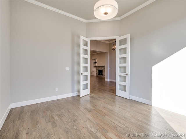 empty room featuring a fireplace, light hardwood / wood-style floors, and ornamental molding