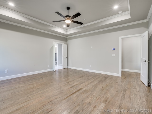 unfurnished room with a raised ceiling, ceiling fan, light wood-type flooring, and ornamental molding